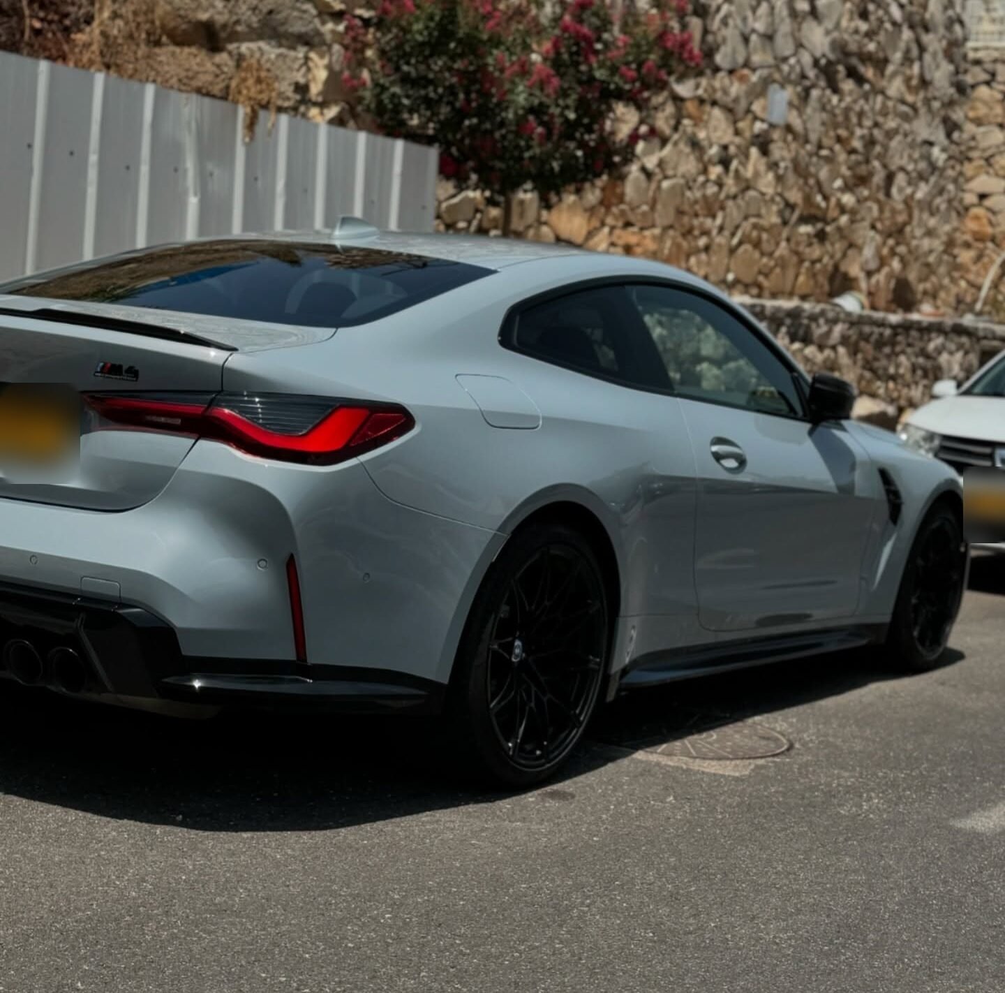 BMW M4 אפורה בהירה מבט שלושת רבעי מאחור עם הפנסים האחוריים