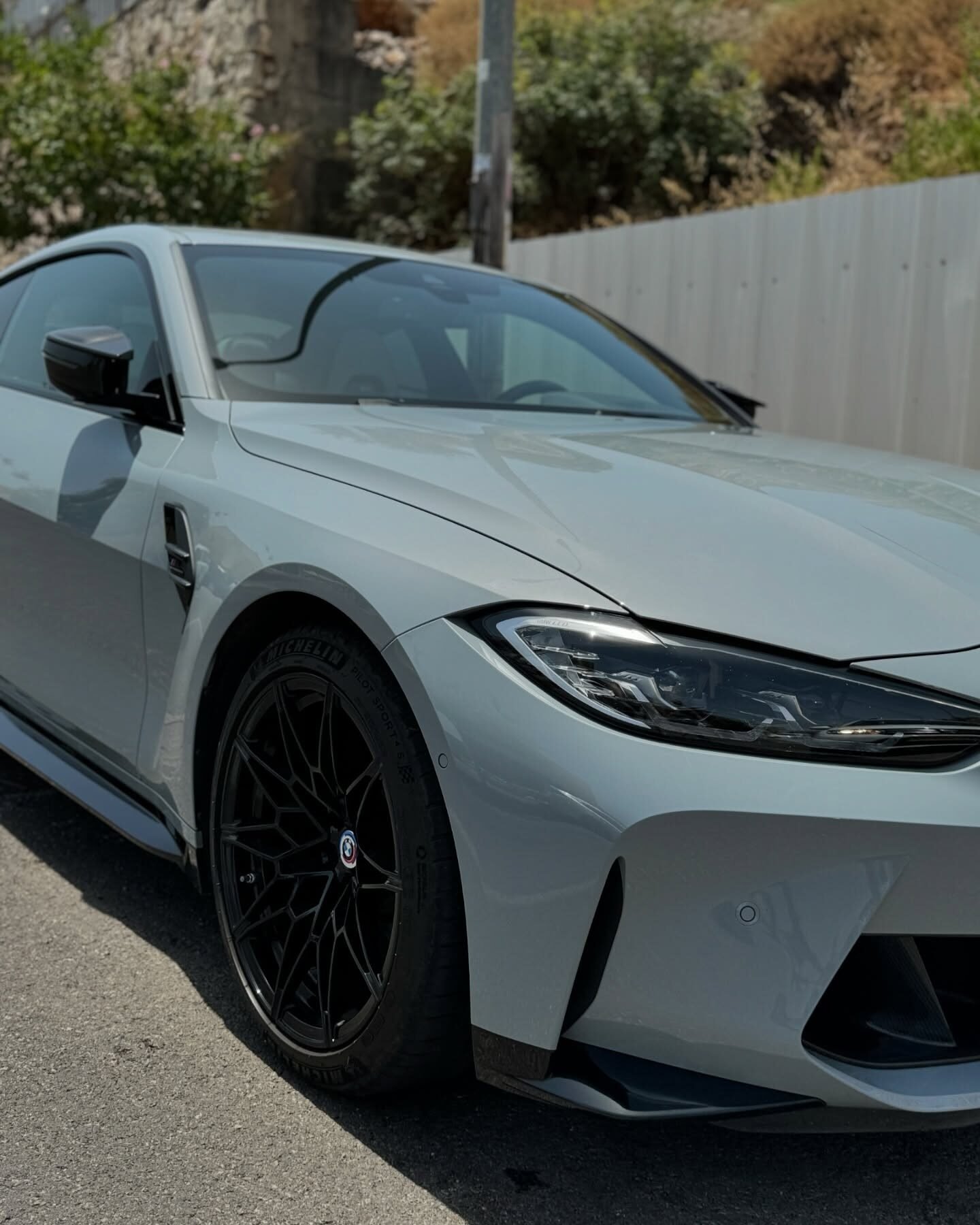 BMW M4 אפורה בהירה מבט שלושת רבעי מלפנים עם חישוקים שחורים
