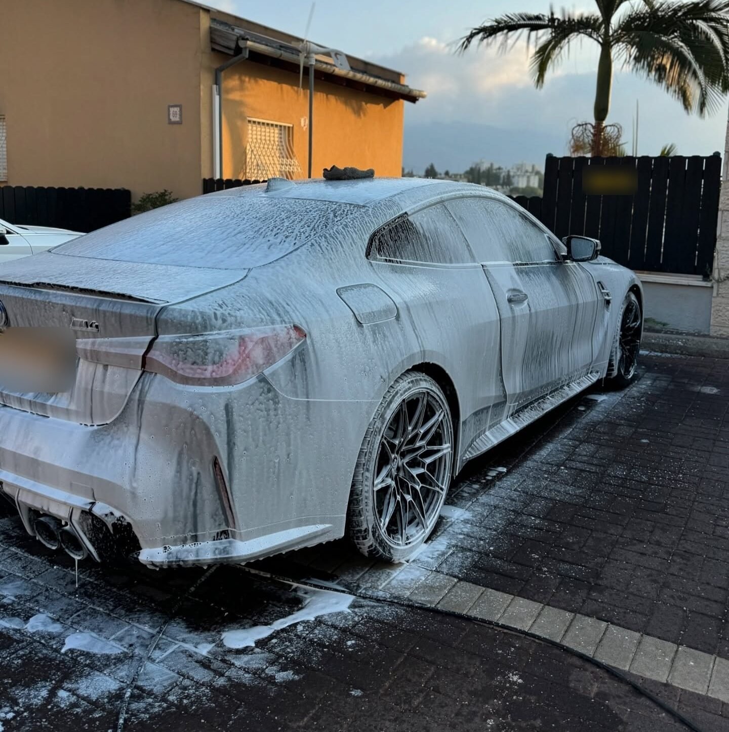BMW M4 מכוסה בקצף שטיפה בחניה ליד בית