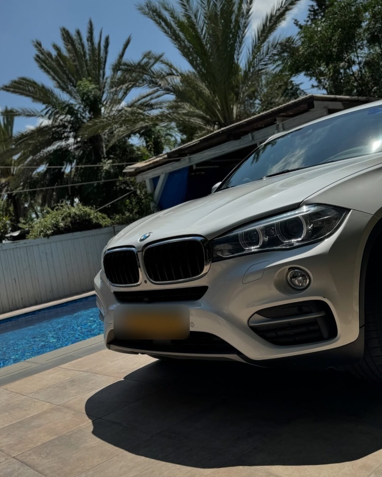 חזית BMW X6 לבנה ליד בריכה, צילום מזווית נמוכה